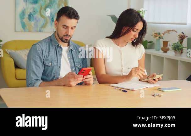 A candid view of a couple concentrating on tasks at a wooden table ...