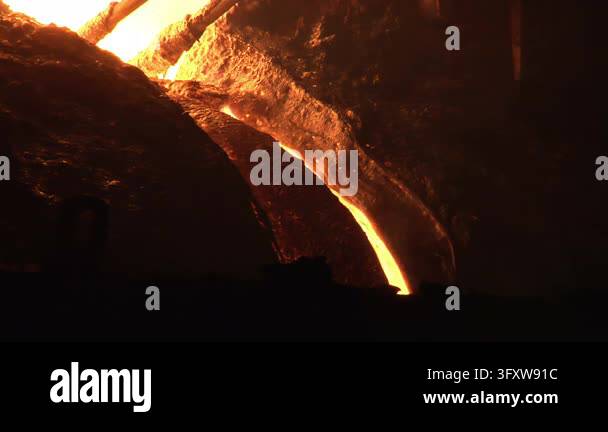 Molten iron stream flowing trough blast furnace, electrodes glowing hot ...