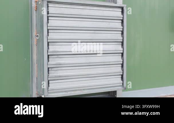 Wall mounted extractor fan spinning fast behind louvered grille, green ...