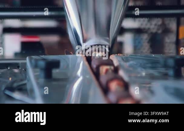 Confectionery production close up, chocolate coated bars with filling ...