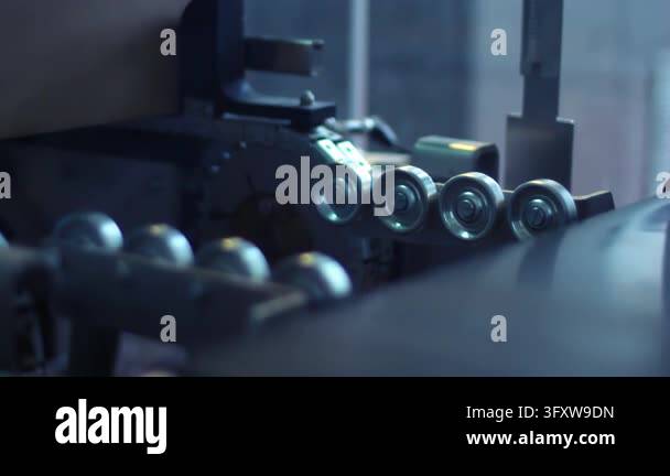 Steel rollers guide box through packing machine close up. Production ...