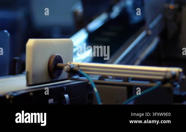 Foil sachets ride conveyor belt past pneumatic cylinder, automated food ...