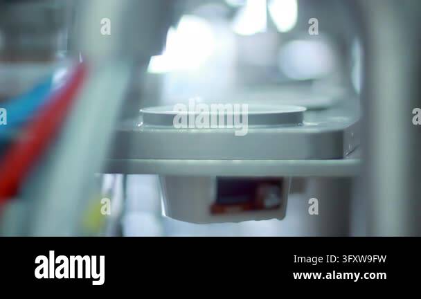 Dairy packaging line closeup, white plastic containers moving through ...
