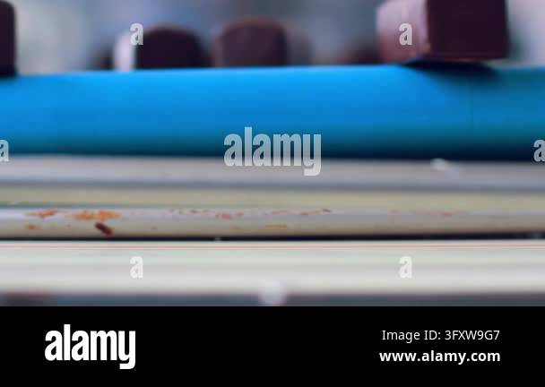 Snac Chocolate Rotating blue roller conveyor belt closeup low angle. Chocolate bars ...