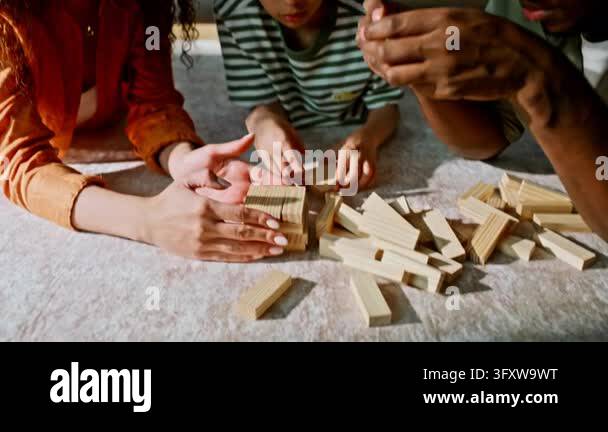 Weekend Teamwork Closeup hands building block tower living room carpet. Diverse parents ...