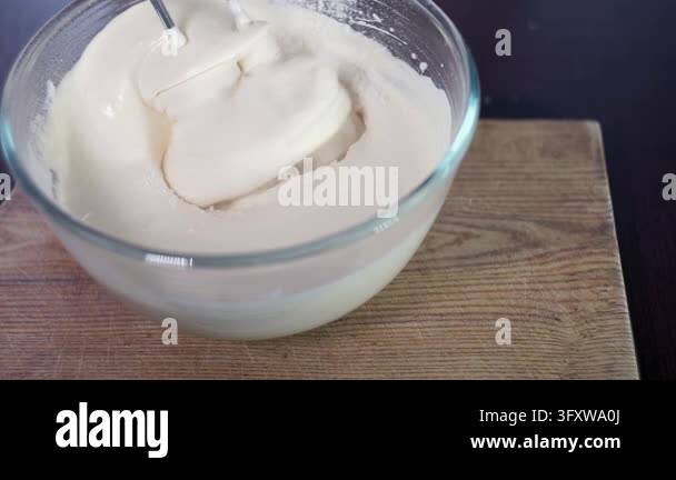 Mixing batter glass bowl closeup, electric mixer blending flour into ...