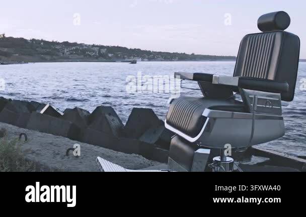 Empty barber chair standing seaside near concrete breakwater, calm sea ...