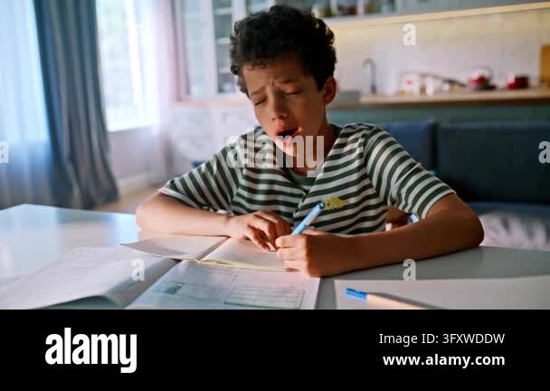 Tired kid struggling homework home kitchen table. African american ...