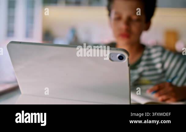 Distance learning home kitchen, mixed race boy watching tablet lesson ...