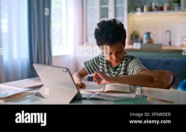 Online lesson home kitchen, child writing notebook with tablet. Tired ...