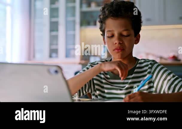 Homework home kitchen, boy writing notebook, digital tablet lesson ...