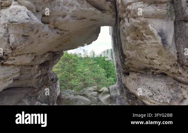 Daylight pours into craggy limestone cave arch, framing view of ...
