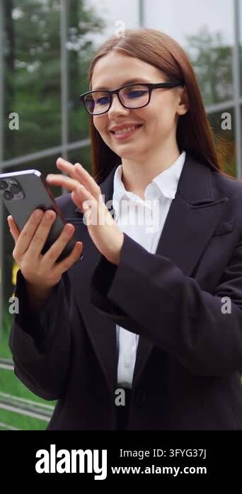 Young woman in formal business attire holding a mobile phone and ...