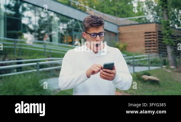 Close up of man holds smartphone, happy to receive notification ...
