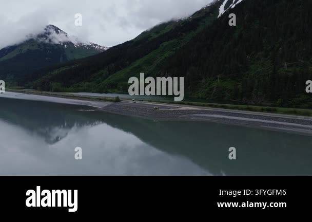 Aerial slow motion view over mirror calm fjord water with a misty snow ...