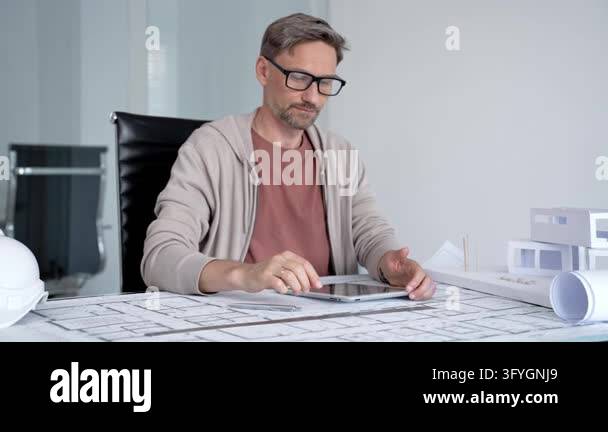 Male architect concentrating on design work, interacting with a tablet ...