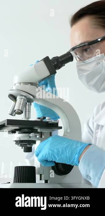 Female scientist working with a microscope, performing medical research ...