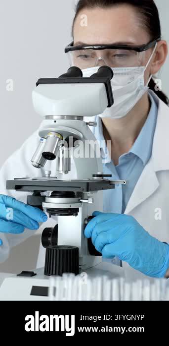 Scientist wearing protective mask, safety glasses, and blue gloves ...