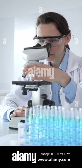 Scientific researcher wearing white lab coat examining sample through ...