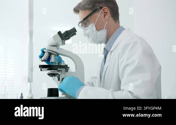 Scientist meticulously examining samples under a microscope in a clean ...