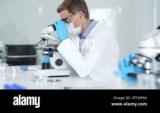 Scientist wearing face mask and gloves performing research using a ...