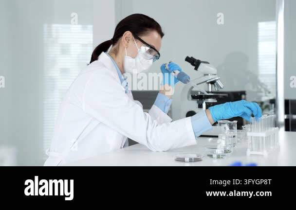 Female researcher working in a sterile laboratory, wearing a mask and ...