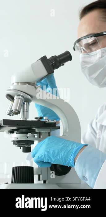 Female scientist working with a microscope, performing medical research ...