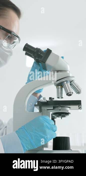 Female scientist working with a microscope, performing medical research ...