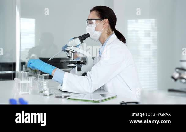 Female researcher working in a sterile laboratory, wearing a mask and ...