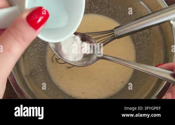 Extinguishing baking soda with vinegar in a spoon over a bowl with ...