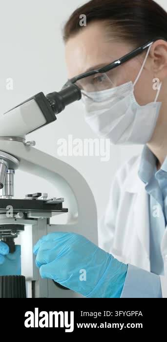 Female scientist working with a microscope, performing medical research ...