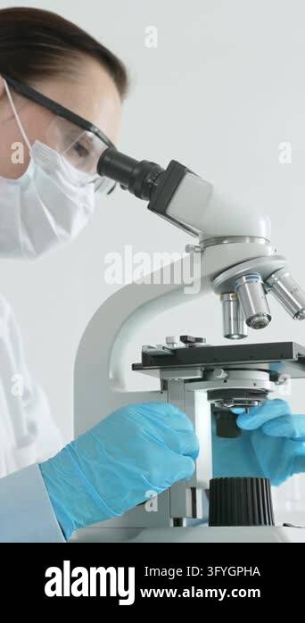 Female scientist working with a microscope, performing medical research ...