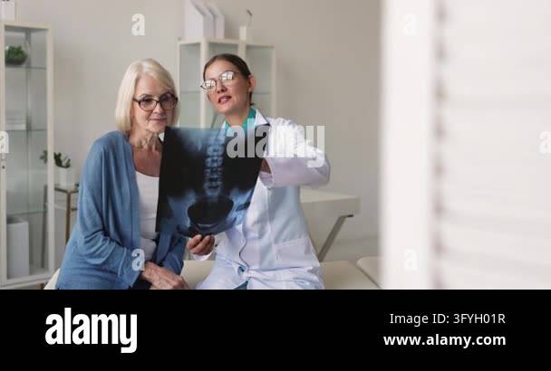Collection Plan Process Doctor surgeon showing xray image to senior woman patient in clinic ...