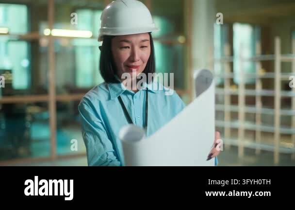 Asian smiling female architect looking in blueprint Chinese woman ...