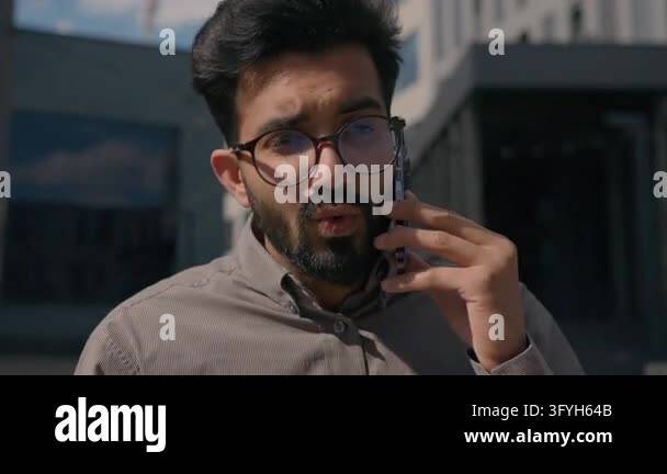 Angry Indian Arabian businessman shouting into smartphone outdoors near ...