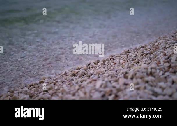Pebble Washed Gentle waves wash over pebble beach Stock Video Footage - Alamy