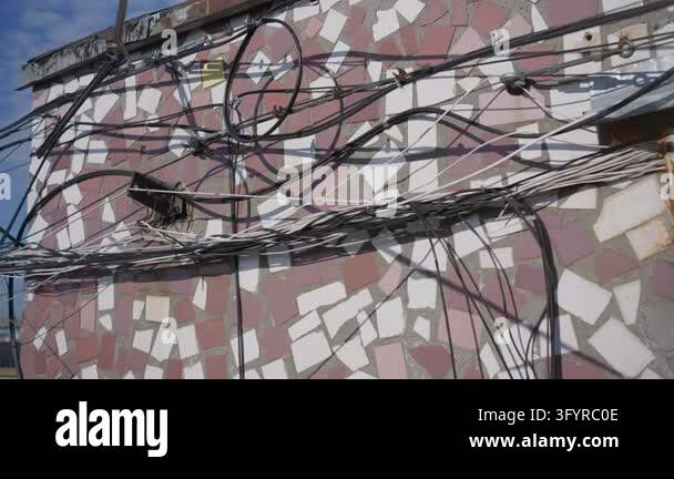 Tangled communication cables hang along the exterior retro mosaic wall ...