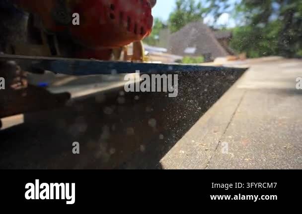 Slow motion of Roofer cutting a wooden board with a circular saw during ...