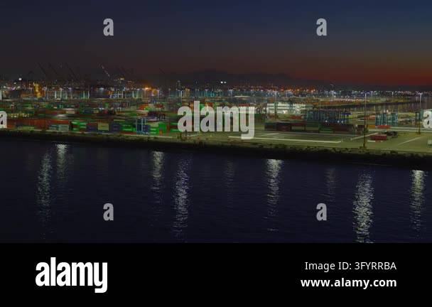 Wide panoramic shot of a brightly lit shipping container terminal at ...