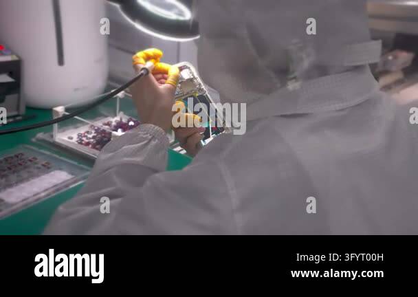 Cleanroom 360 Worker inspecting smartphone back cover under lamp. Clean room. Mobile ...
