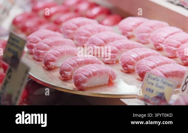 In slow motion, pink tuna slices rest on rice portions arranged across ...