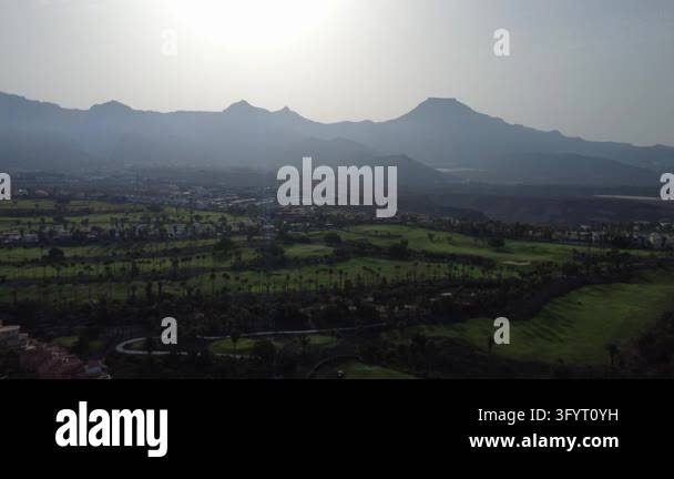 Aerial drone view of a golf course at sunrise beneath the hazy ...