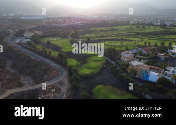 Aerial drone view of a winding road beside golf course fairways and ...