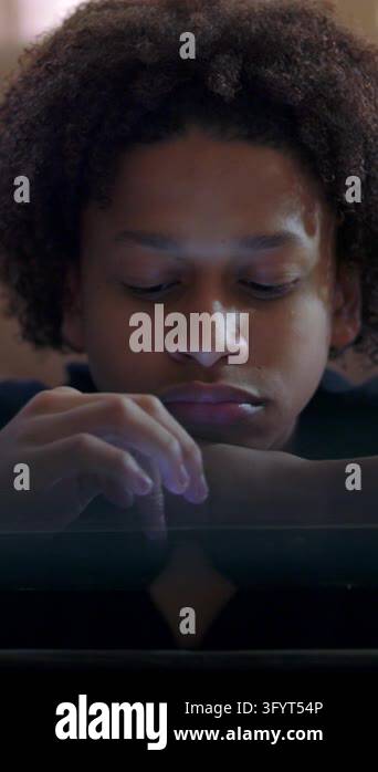 Tired teenage male browsing mobile screen with indifferent expression ...