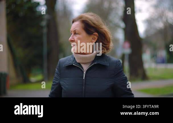Older Caucasian woman walking in the park turns around startled and ...