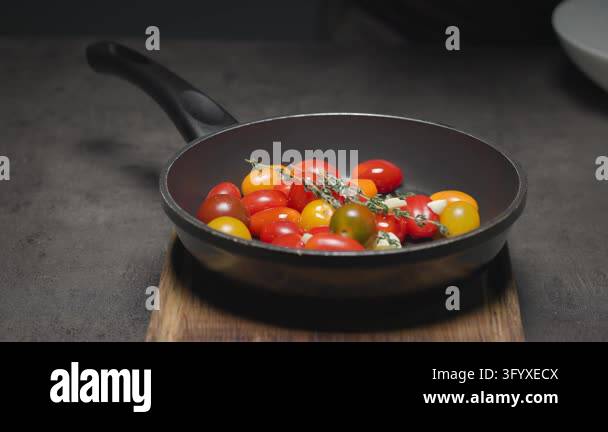 chef sprinkles salt on tomatoes in pan and moves the pan from wooden ...