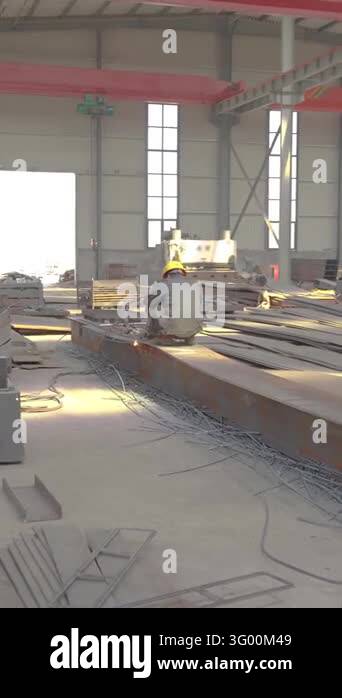 Industrial worker working on a large steel beam in a fabrication ...