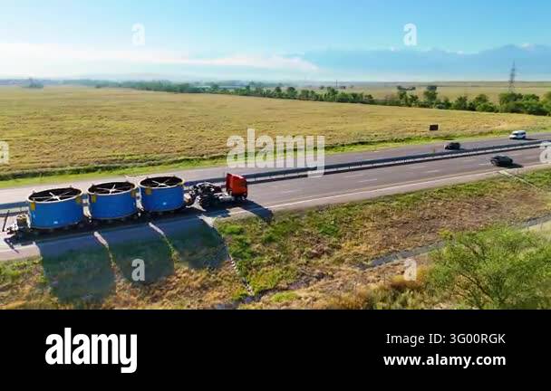Interstate Side View Heavy haulage of three large blue cylindrical industrial cargo units on ...