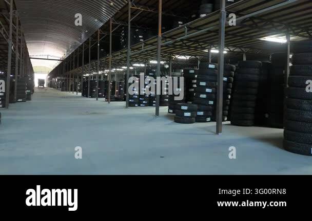 Tracking view past rows of stacked tires and steel columns beneath an ...