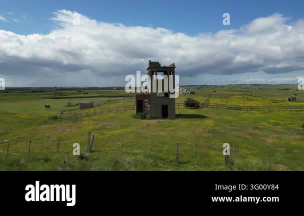 Abandoned building structure standing alone in a green field under a ...